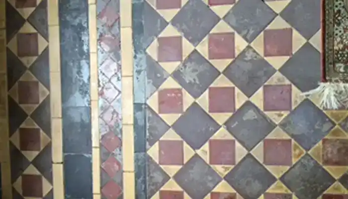 Minton tile hallway floor in Ovington covered in dark residue before restoration